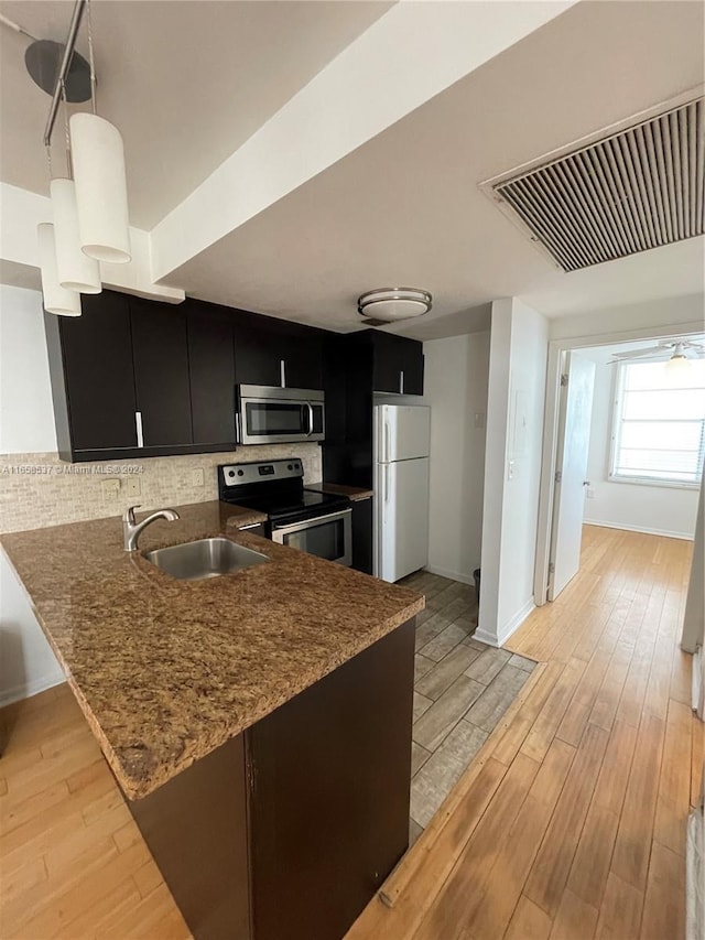 kitchen featuring pendant lighting, light hardwood / wood-style flooring, stainless steel appliances, kitchen peninsula, and sink