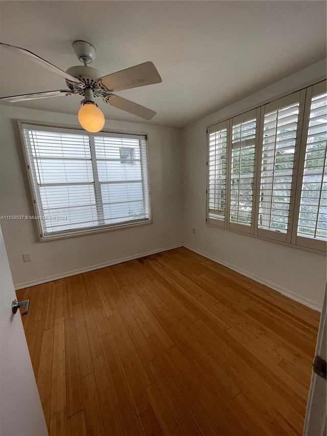 spare room with plenty of natural light, hardwood / wood-style flooring, and ceiling fan