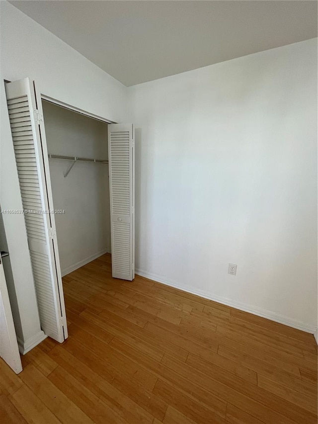 unfurnished bedroom featuring hardwood / wood-style floors and a closet