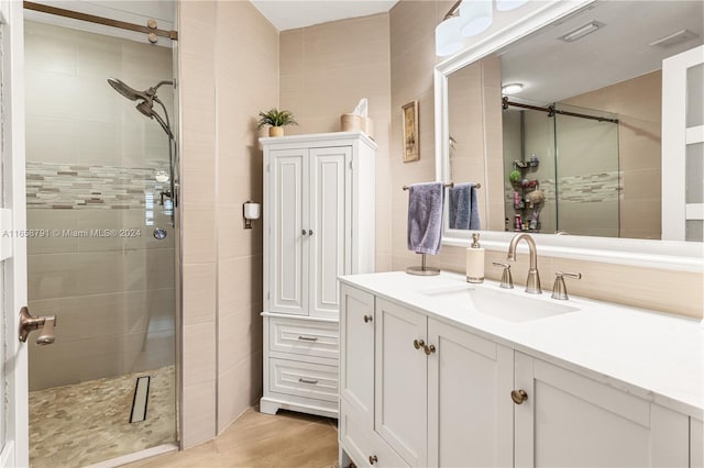 bathroom featuring tile walls, an enclosed shower, and vanity