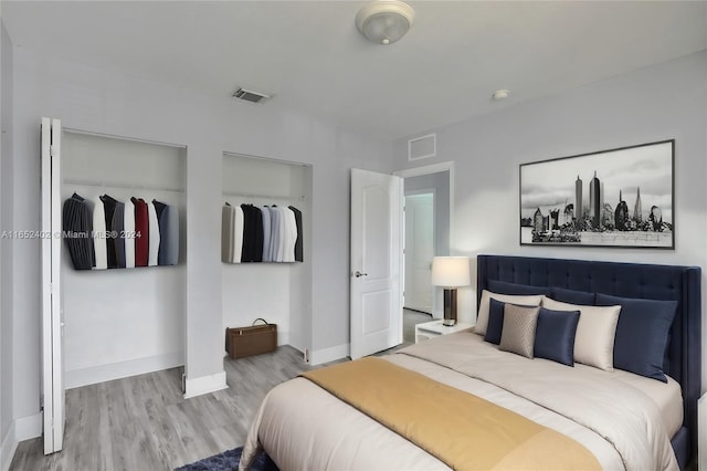 bedroom featuring two closets and light hardwood / wood-style floors