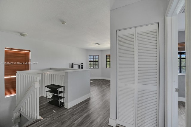 hall featuring dark wood-type flooring and a textured ceiling