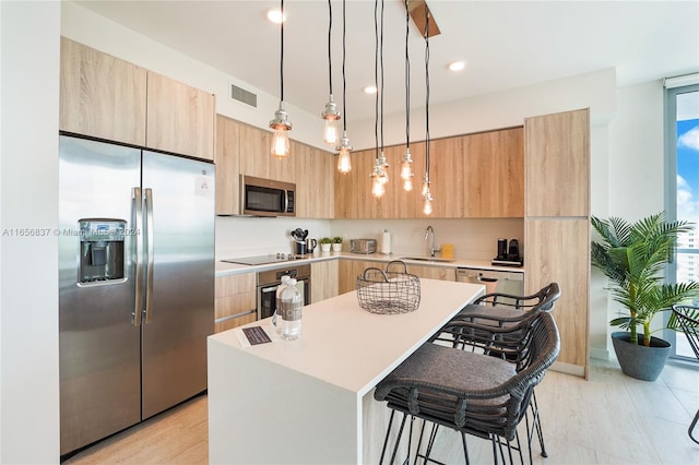 kitchen featuring appliances with stainless steel finishes, a breakfast bar, a kitchen island, pendant lighting, and a wealth of natural light