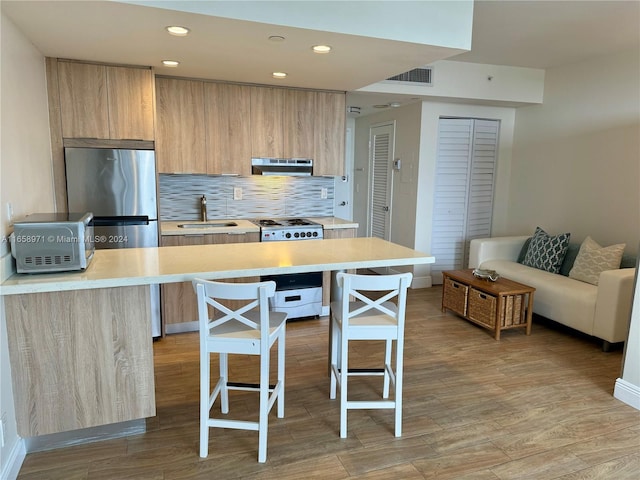 kitchen with a kitchen island, stainless steel appliances, a breakfast bar, and light hardwood / wood-style flooring