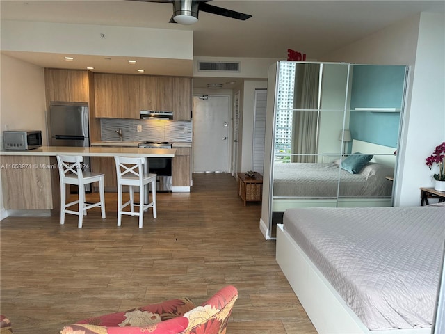 bedroom featuring light wood-type flooring, stainless steel fridge, and ceiling fan