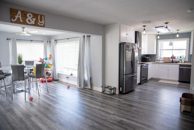 kitchen with white cabinets, appliances with stainless steel finishes, dark hardwood / wood-style floors, and a textured ceiling