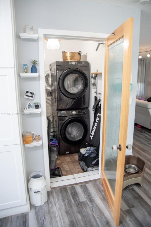 laundry room featuring dark wood-type flooring and stacked washer / drying machine