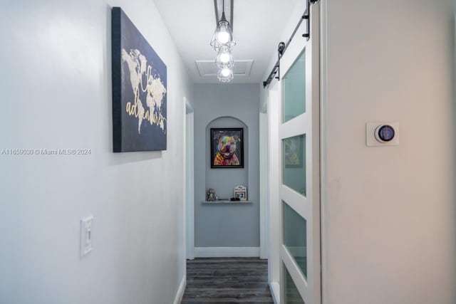 hallway with a barn door and dark hardwood / wood-style floors