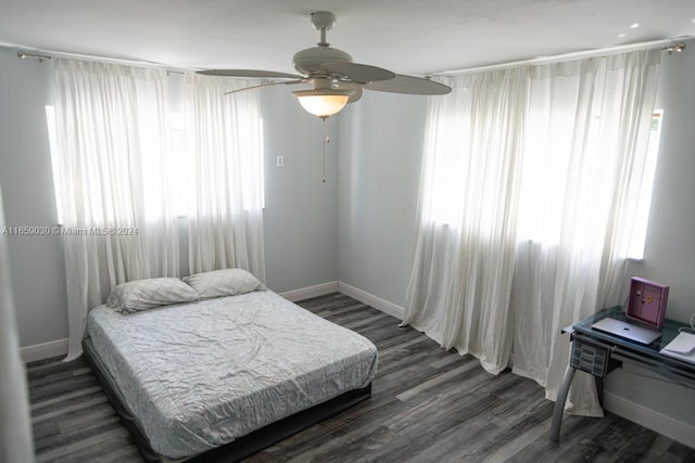 bedroom featuring multiple windows, dark wood-type flooring, and ceiling fan