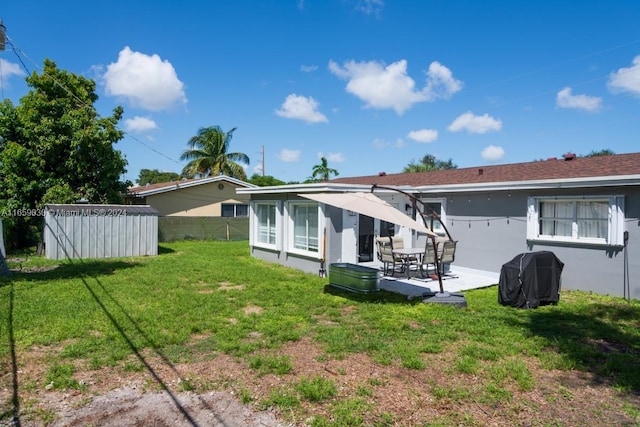 back of property with a yard, a storage unit, and a patio