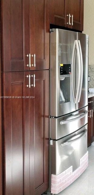 kitchen with stainless steel refrigerator with ice dispenser and light stone counters