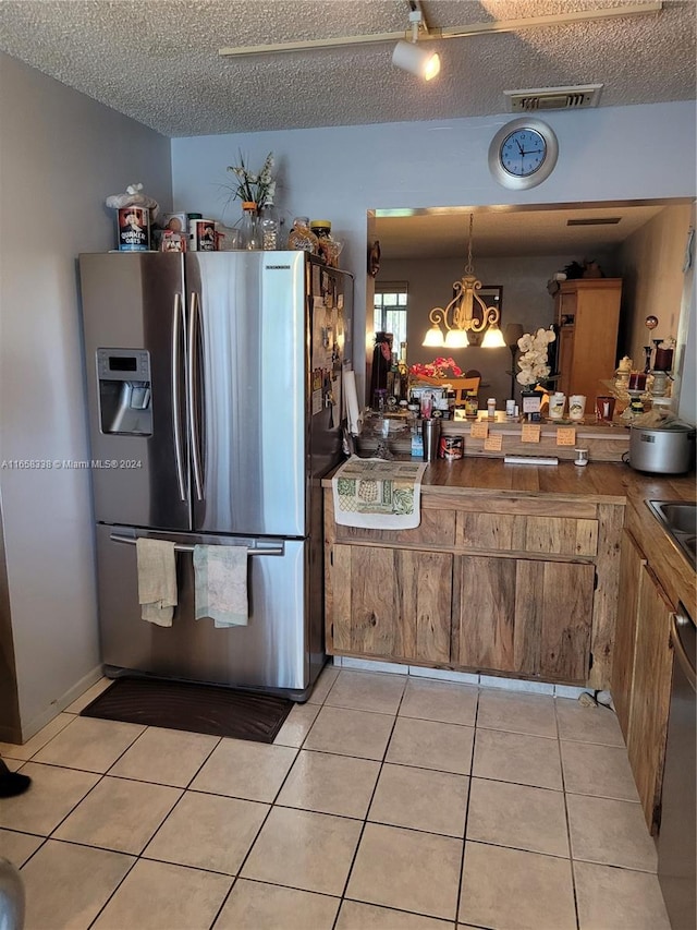 kitchen featuring a notable chandelier, a textured ceiling, light tile patterned floors, stainless steel appliances, and hanging light fixtures