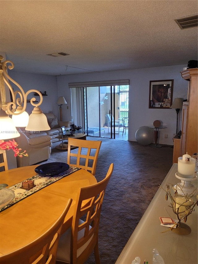 dining area with a textured ceiling and dark colored carpet