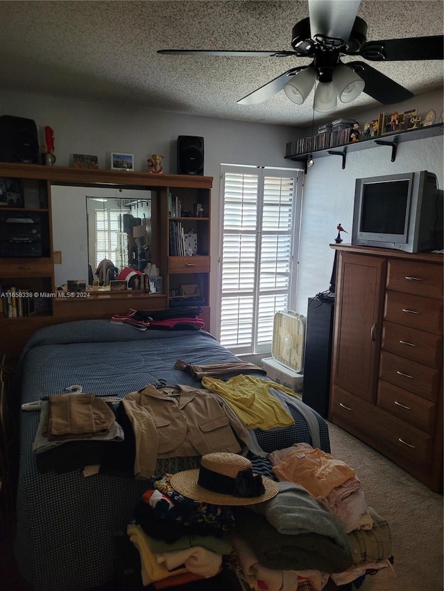 bedroom with a textured ceiling, carpet flooring, and ceiling fan