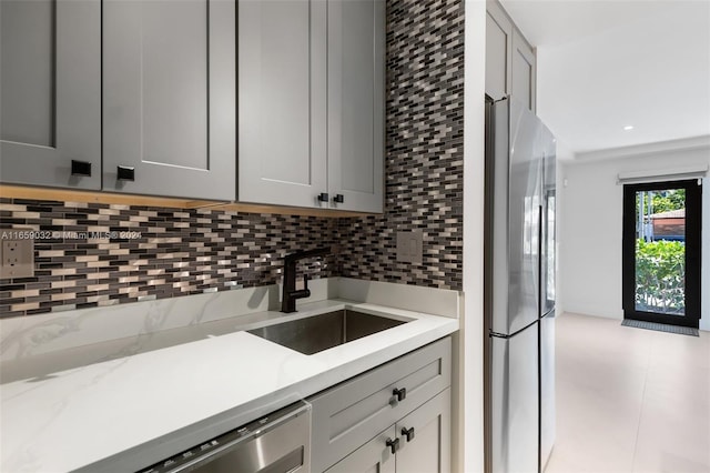 kitchen with light tile patterned floors, appliances with stainless steel finishes, sink, gray cabinets, and tasteful backsplash