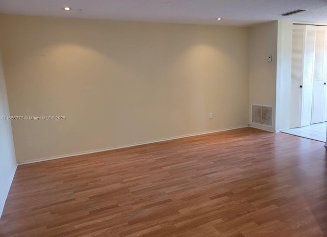 spare room with baseboards, light wood-style flooring, visible vents, and recessed lighting