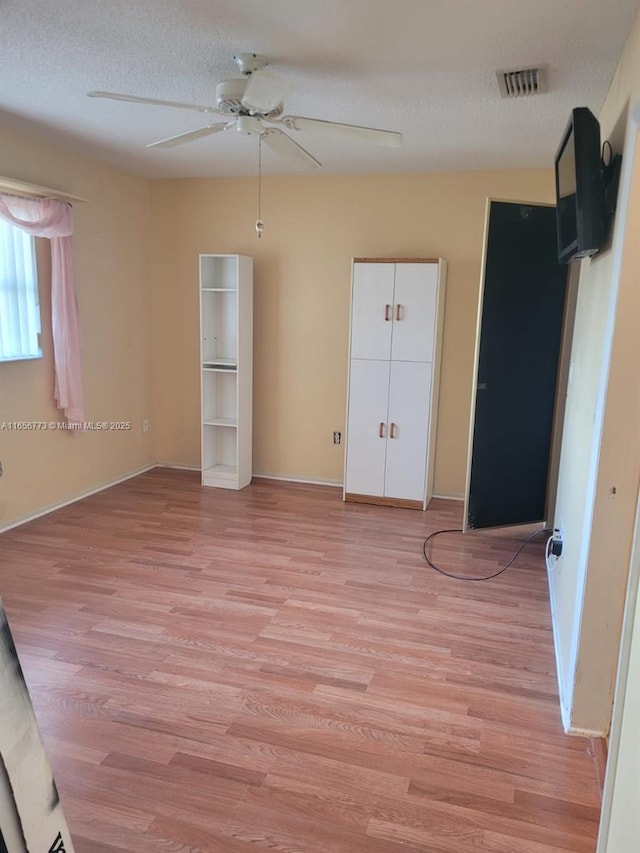 unfurnished bedroom with light wood finished floors, visible vents, baseboards, ceiling fan, and a textured ceiling