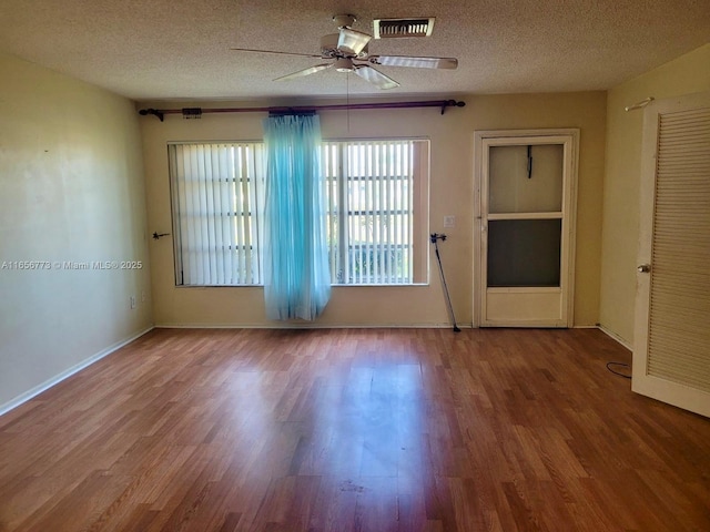 empty room featuring a textured ceiling, wood finished floors, and visible vents