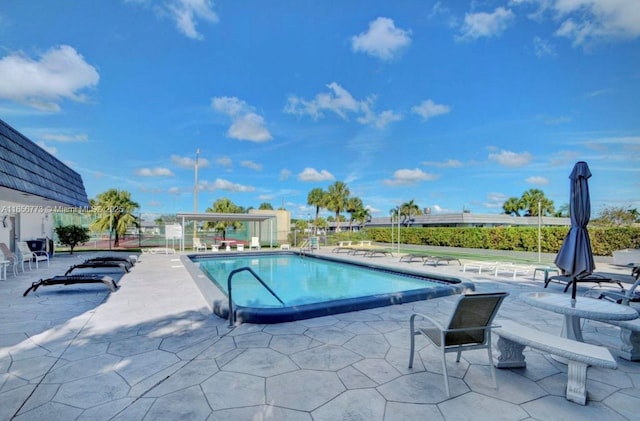 community pool with a patio area and fence