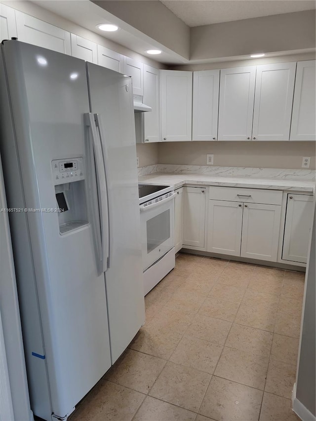 kitchen with white cabinets, light stone countertops, and white appliances