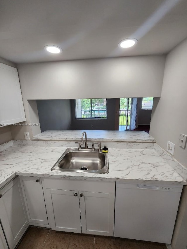 kitchen with white cabinets, white dishwasher, kitchen peninsula, and sink