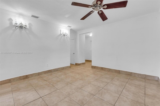 tiled empty room featuring ceiling fan and ornamental molding