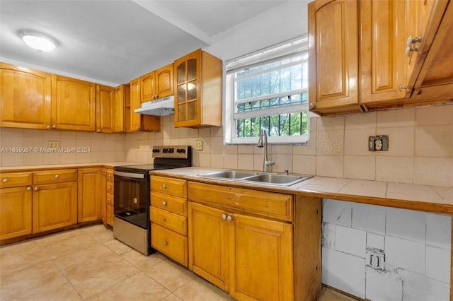 kitchen featuring light tile patterned floors, stainless steel electric range oven, tile counters, sink, and decorative backsplash