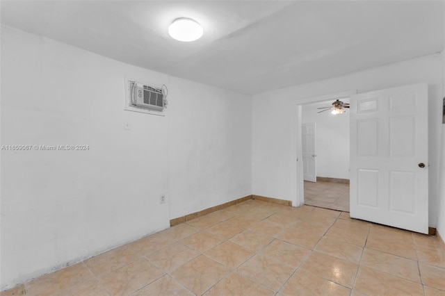 unfurnished room featuring a wall unit AC, light tile patterned floors, and ceiling fan