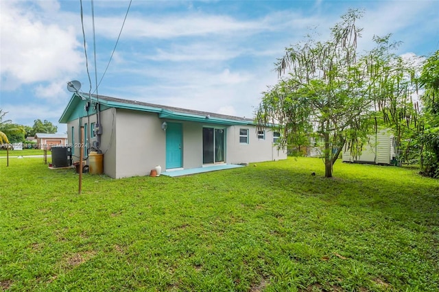 rear view of house featuring central AC and a yard