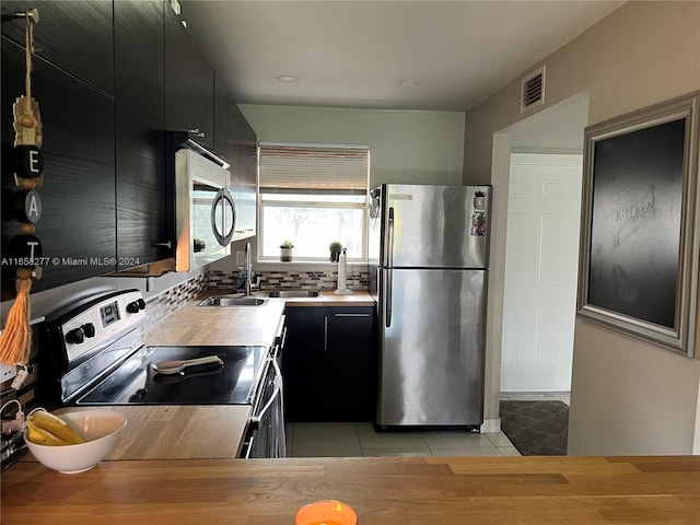 kitchen featuring stainless steel appliances, sink, light tile patterned floors, and backsplash