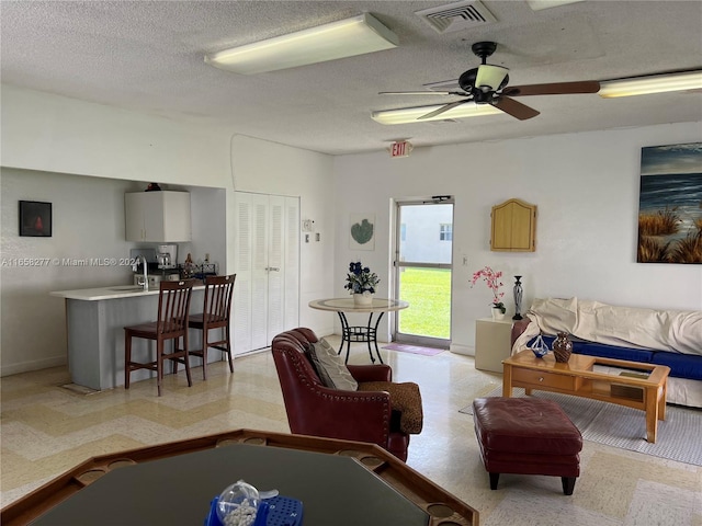 living room with a textured ceiling, sink, and ceiling fan