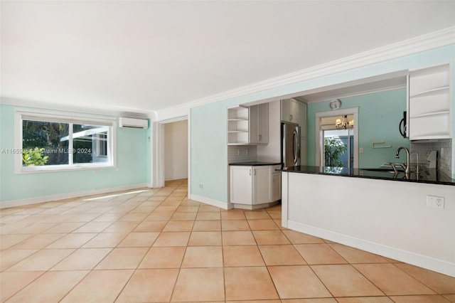 kitchen with light tile patterned flooring, decorative backsplash, stainless steel appliances, an inviting chandelier, and a wall mounted air conditioner