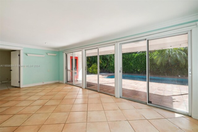 tiled empty room featuring ornamental molding and plenty of natural light