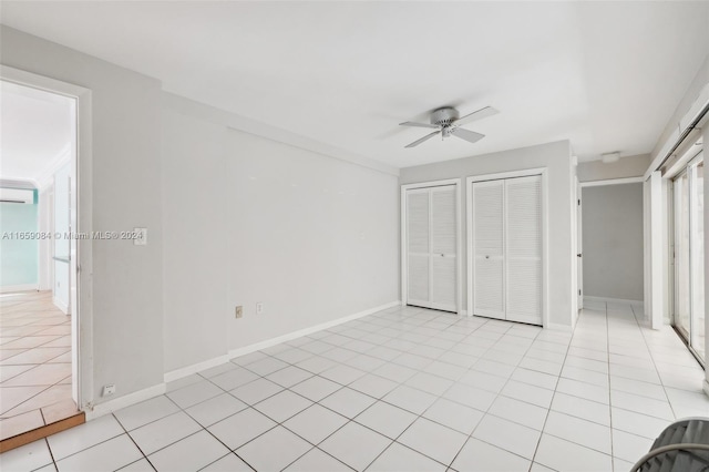 unfurnished bedroom featuring multiple closets, ceiling fan, light tile patterned floors, and a wall mounted air conditioner