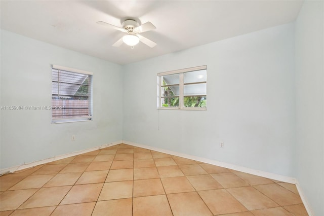 spare room with ceiling fan and light tile patterned floors