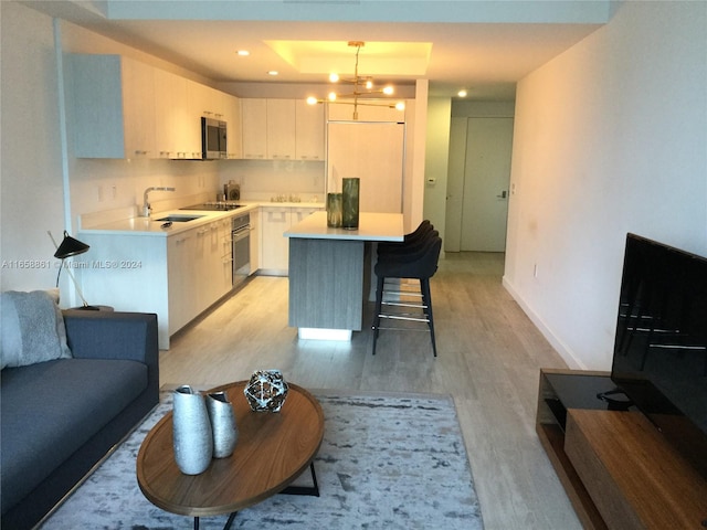 kitchen with a notable chandelier, white cabinets, light hardwood / wood-style flooring, stainless steel appliances, and decorative light fixtures