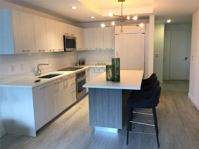 kitchen with a notable chandelier, a kitchen island, light hardwood / wood-style flooring, appliances with stainless steel finishes, and decorative light fixtures