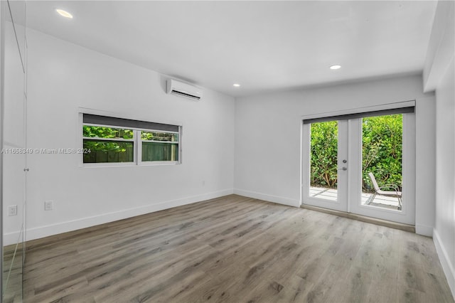 empty room with wood-type flooring and a wall mounted air conditioner