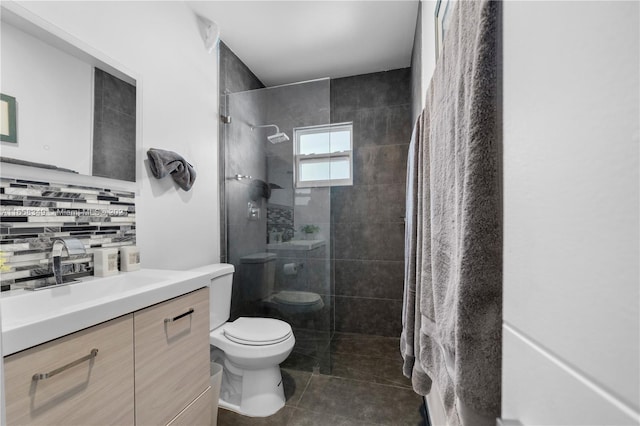 bathroom featuring tile patterned flooring, vanity, toilet, and a tile shower