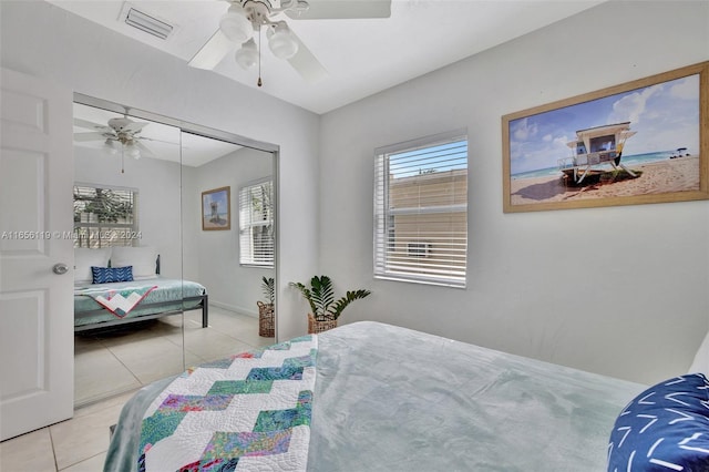 tiled bedroom with ceiling fan and a closet