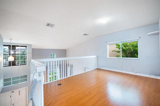 unfurnished room featuring lofted ceiling, hardwood / wood-style flooring, and a healthy amount of sunlight