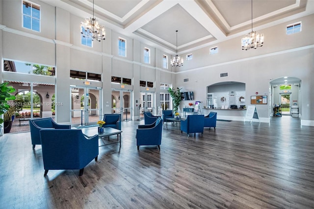 living room featuring a healthy amount of sunlight, a high ceiling, a notable chandelier, and wood-type flooring