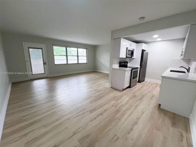 kitchen with sink, white cabinets, stainless steel appliances, and light hardwood / wood-style floors