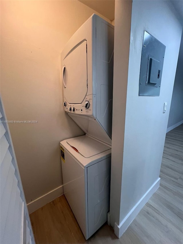 clothes washing area featuring light hardwood / wood-style floors, electric panel, and stacked washer and clothes dryer