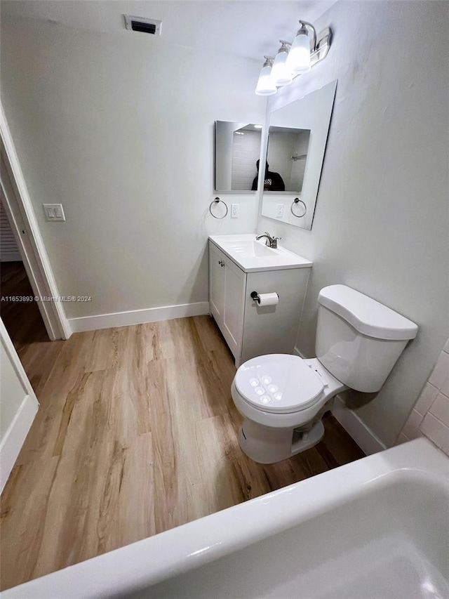 bathroom featuring vanity, toilet, a tub, and hardwood / wood-style floors