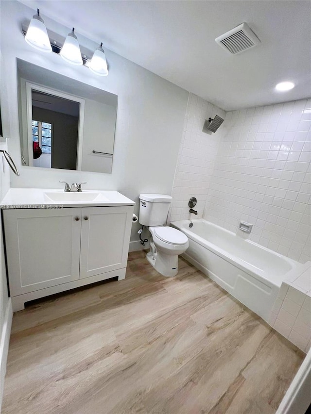 full bathroom featuring toilet, tiled shower / bath, hardwood / wood-style flooring, and vanity