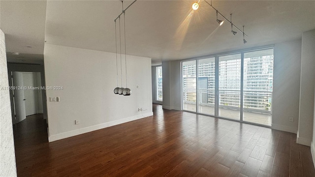 empty room with rail lighting, expansive windows, and dark hardwood / wood-style flooring