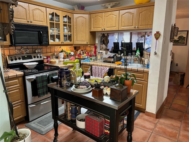 kitchen featuring tile countertops, stainless steel range with electric cooktop, decorative backsplash, light tile patterned floors, and a textured ceiling