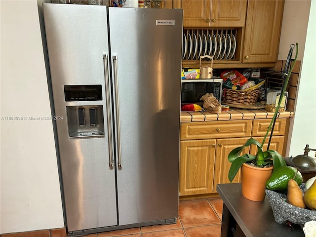 kitchen with tile counters, light tile patterned floors, and stainless steel appliances