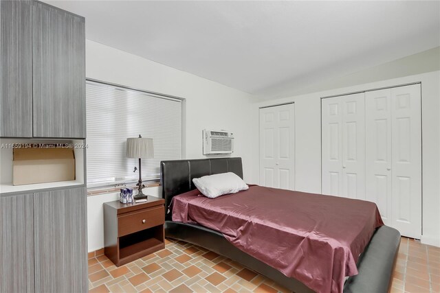 bedroom with an AC wall unit and multiple closets